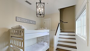 Habitación con literas, una escalera y un cartel que dice 'SUNSHINE & SALT WATER'.