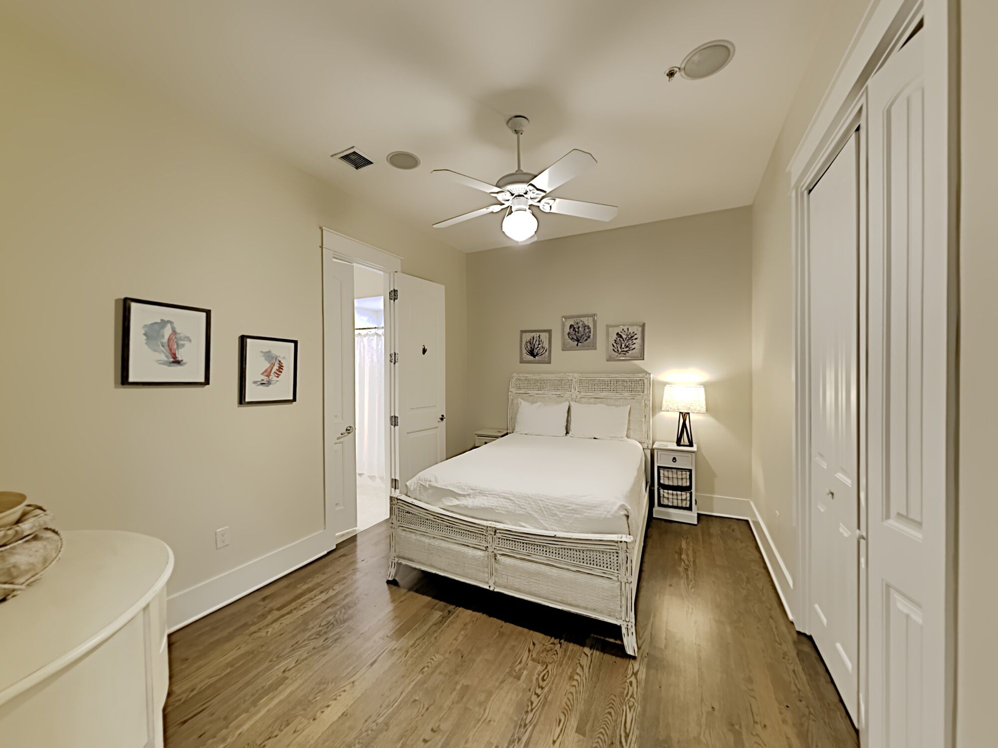 A bedroom with a bed, a ceiling fan, a nightstand, and a door.