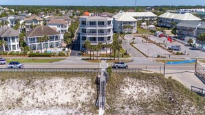 A coastal residential area with multi-story buildings, a parking lot, and a beach in the foreground.