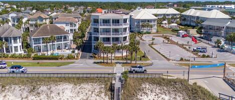 A coastal residential area with multi-story buildings, a parking lot, and a beach in the foreground.