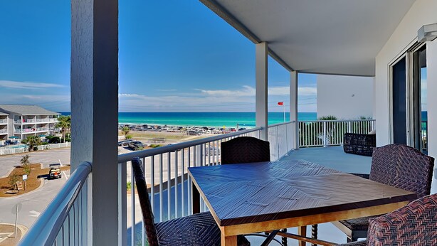 A balcony with a view of the beach and ocean.