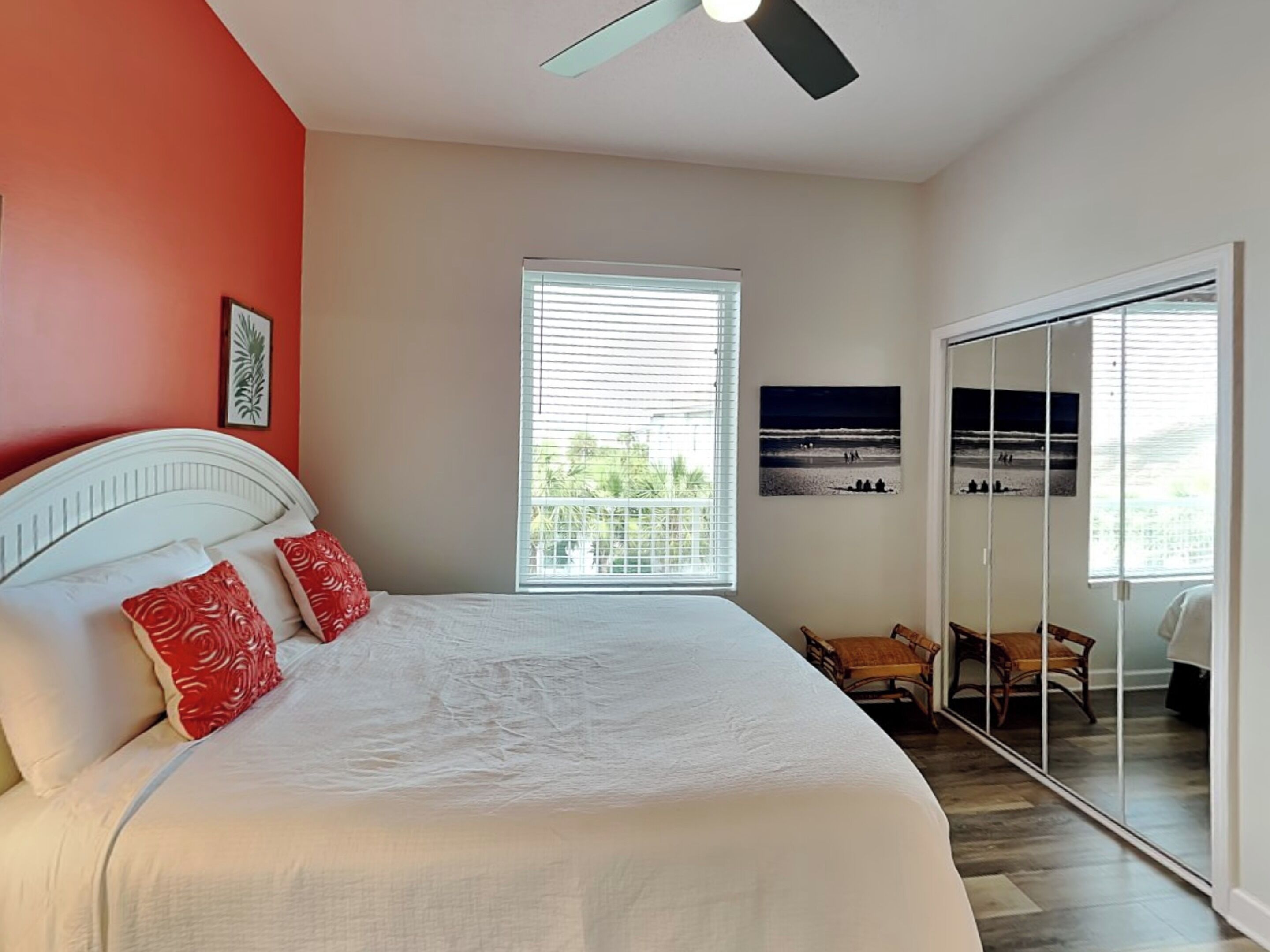 A bedroom with a bed, a ceiling fan, a window with blinds, a balcony, and a door leading to a balcony.