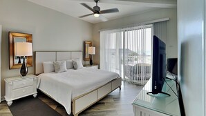A hotel room with a bed, nightstands, a TV, and a balcony with a view.