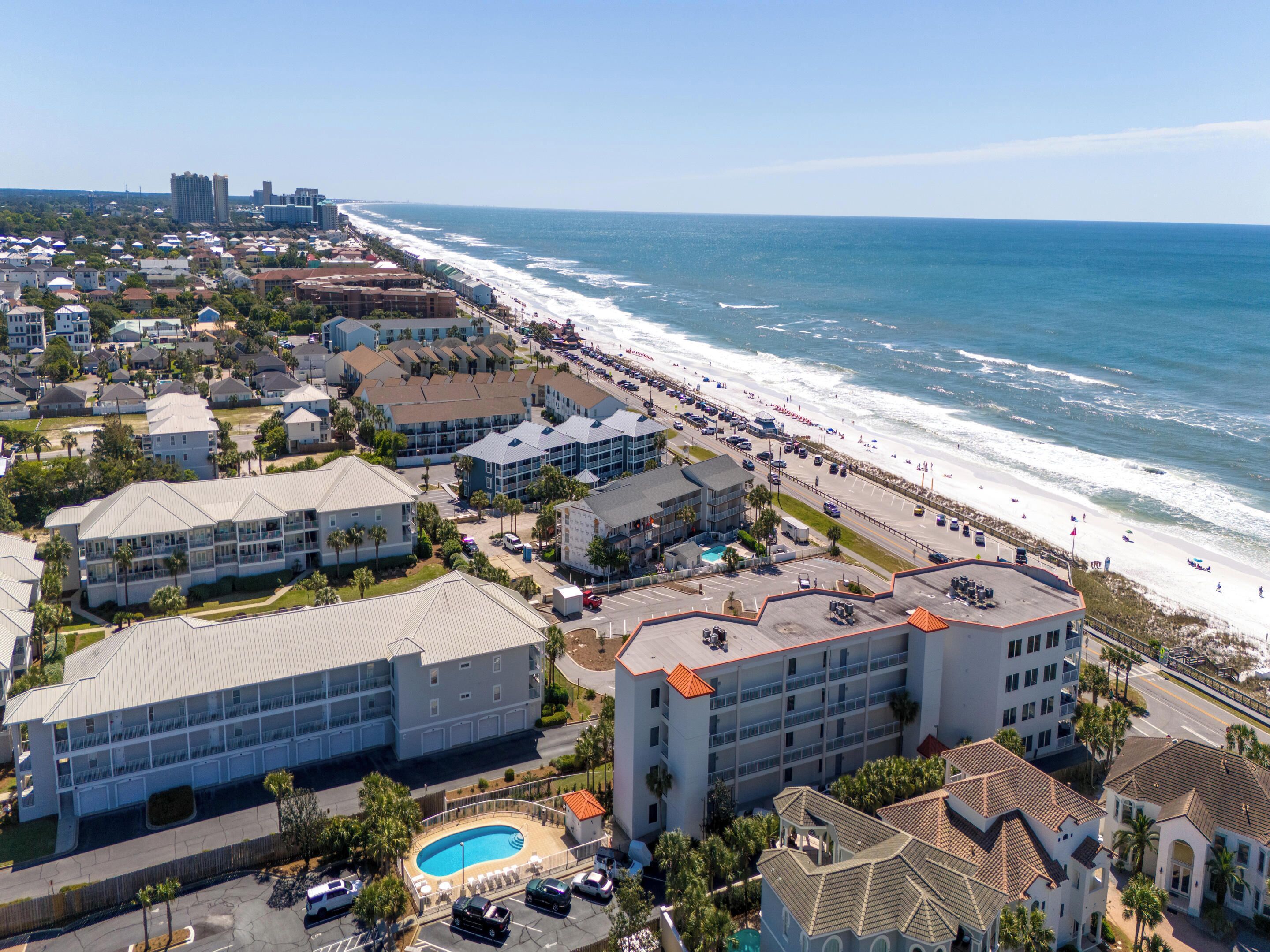 A coastal hotel with multiple buildings, a swimming pool, and a beach view.