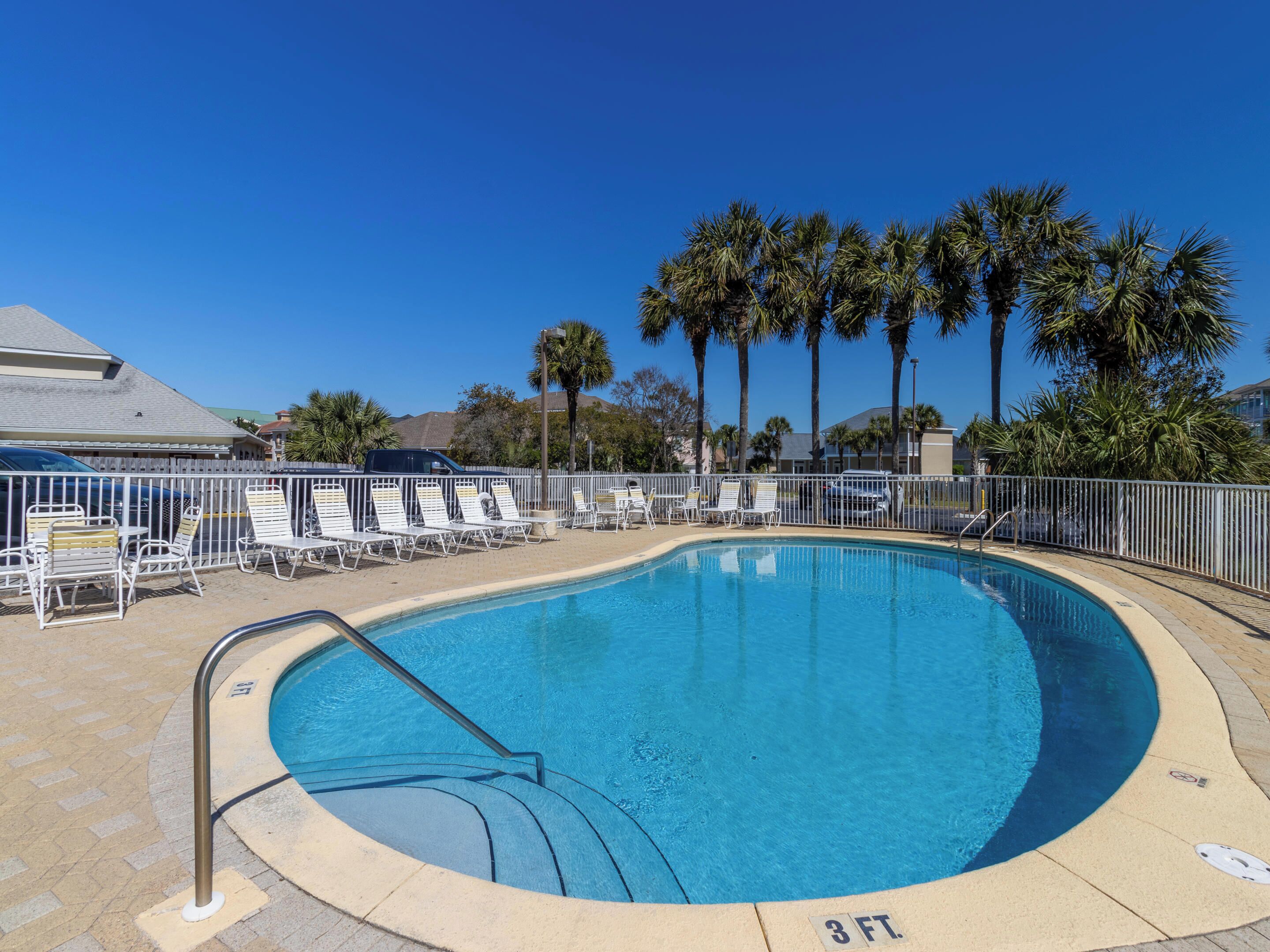 A swimming pool with lounge chairs and palm trees in the background.