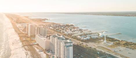 An aerial view of a coastal hotel area with multiple high-rise buildings, a beach, and a marina.