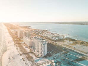 Luchtbeeld van een kusthotelgebied met meerdere hoge gebouwen, een strand en een jachthaven.