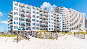 Een meerlaags hotel aan het strand, met balkons en een helder uitzicht op de oceaan.