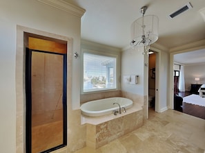 A spacious bathroom with a large bathtub, a shower, and a chandelier.