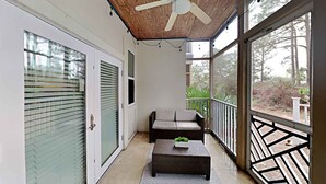 A balcony with a sofa, a small table, and a ceiling fan. - Seagrove Highlands by Southern Vacation Rentals (Santa Rosa Beach)