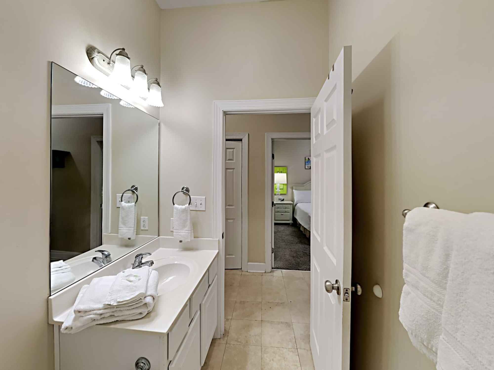 A hotel bathroom with a large mirror, two sinks, and a towel rack.