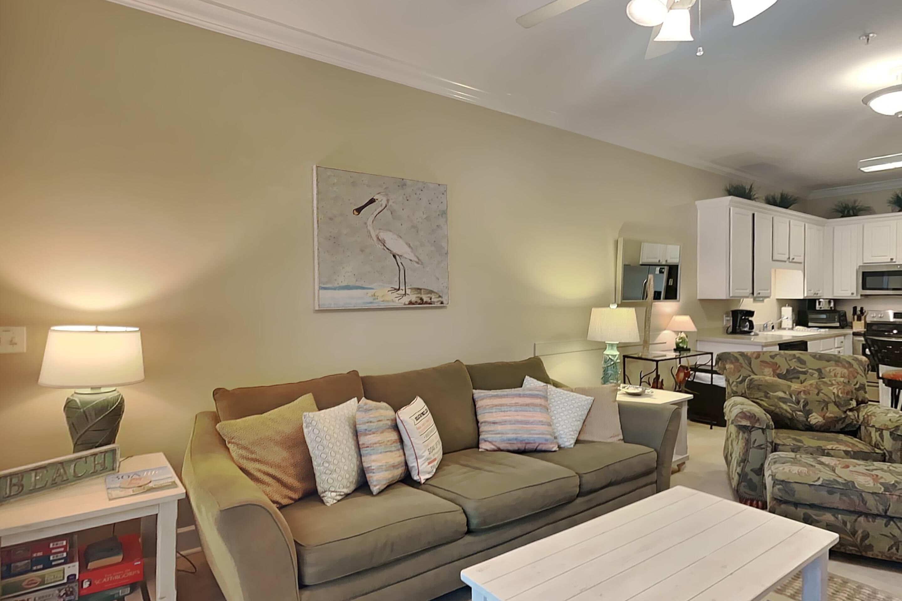 A living room with a sofa, a coffee table, a lamp, and a painting of a bird.