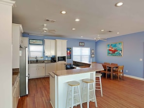 A kitchen with white cabinets, a granite countertop, and a bar area with stools.