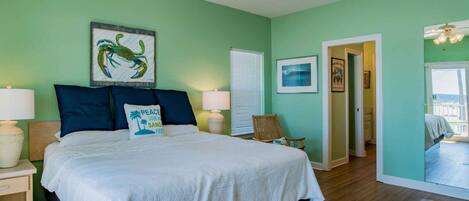 A bedroom with a bed, two bedside tables, a ceiling fan, and a view of a balcony.