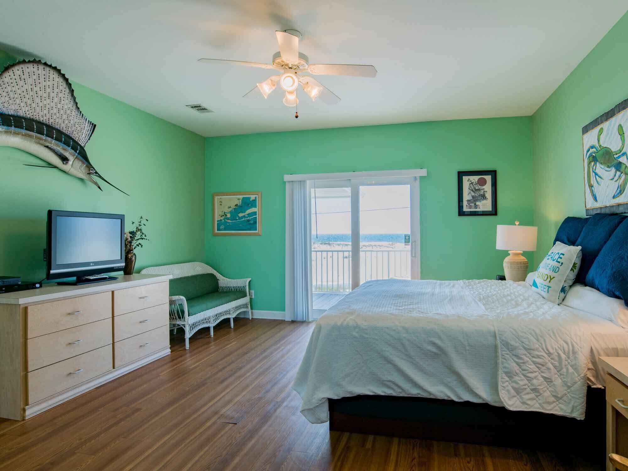 A room with a bed, a TV, a ceiling fan, a window with a view, and a wall-mounted fish decoration.