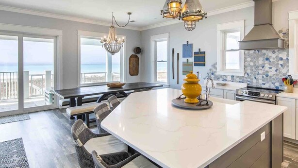 A modern kitchen with a large island, pendant lighting, and a view to the outside. - The Oasis by Resort Collection (Panama City Beach)