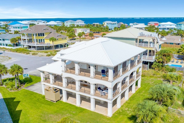 A multi-story beachfront property with balconies, a swimming pool, and a view of the ocean.