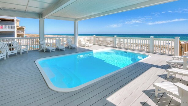 A covered swimming pool with lounge chairs and a view of the beach. - Arena Blanca by Southern Vacation Rentals (Gulf Shores)