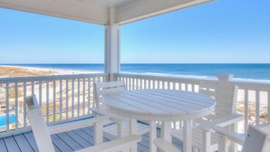 A covered outdoor area with a white table and chairs, overlooking a beach with a clear view of the ocean. - Arena Blanca by Southern Vacation Rentals (Gulf Shores)