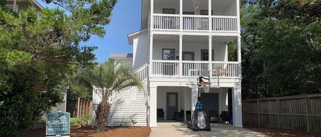 Un immeuble blanc à deux étages, doté d’un balcon, d’un panier de basketball et d’une enseigne indiquant « Southern Magacation Rentals ».