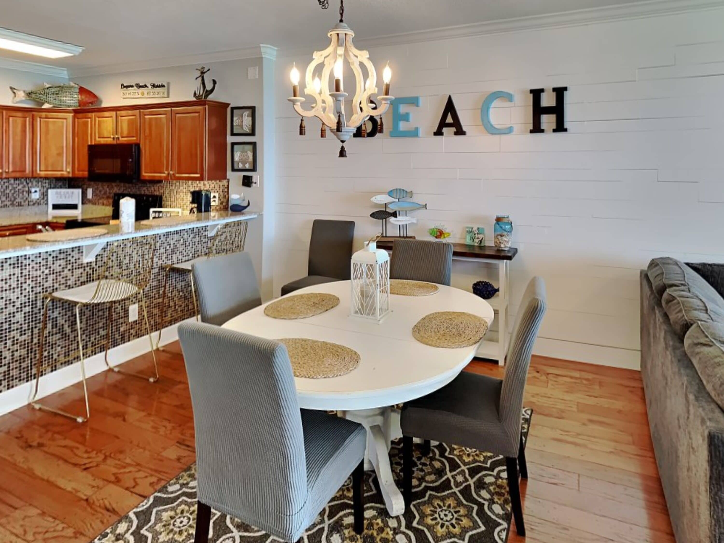 A dining area with a white table, grey chairs, and a chandelier.