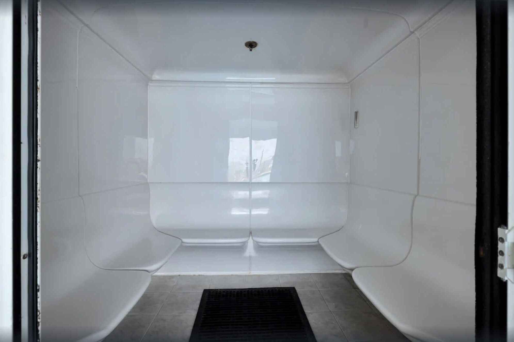 A room with a large window, a door, and a black mat at the entrance.
