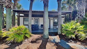 Une maison moderne dotée d’un patio, entourée de palmiers et de plantes tropicales.