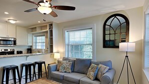 Un salon avec un canapé gris, une table basse et un ventilateur de plafond.