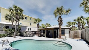 Un jardin avec une piscine, des palmiers et un patio couvert.