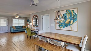 A spacious dining area with a wooden table and bench, a green armchair, and a ceiling fan. - Big Blue by Southern Vacation Rentals (Gulf Shores)