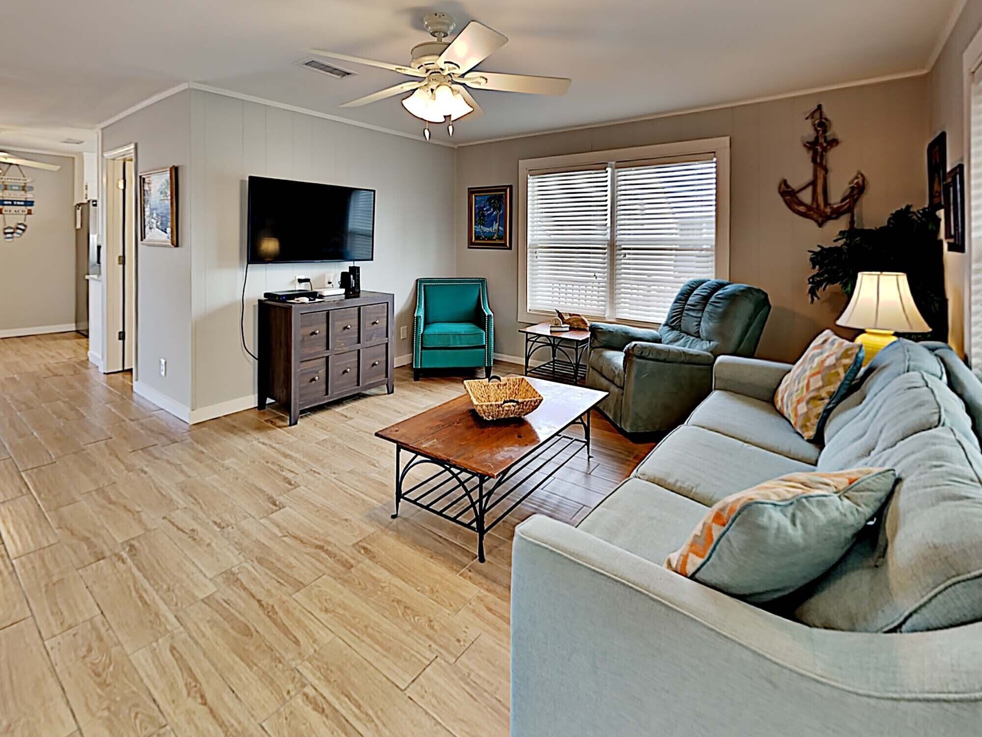 A living room with a sofa, a coffee table, a TV, and a ceiling fan.