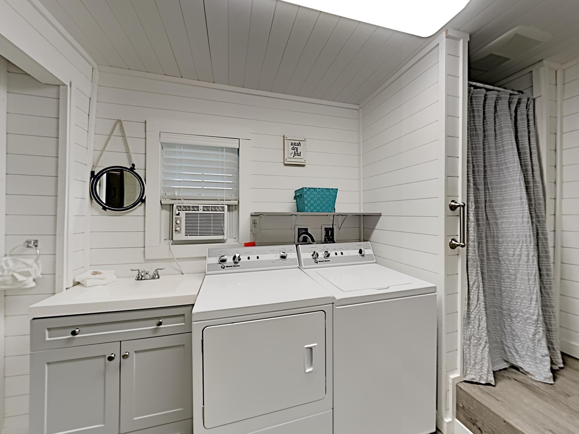 A laundry room with a washing machine, dryer, and a window with blinds.