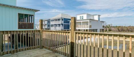A wooden deck with a view of beachfront buildings.