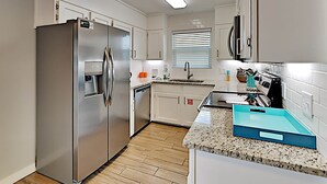 A modern kitchen with stainless steel appliances, white cabinetry, and a granite countertop. - Big Blue by Southern Vacation Rentals (Gulf Shores)