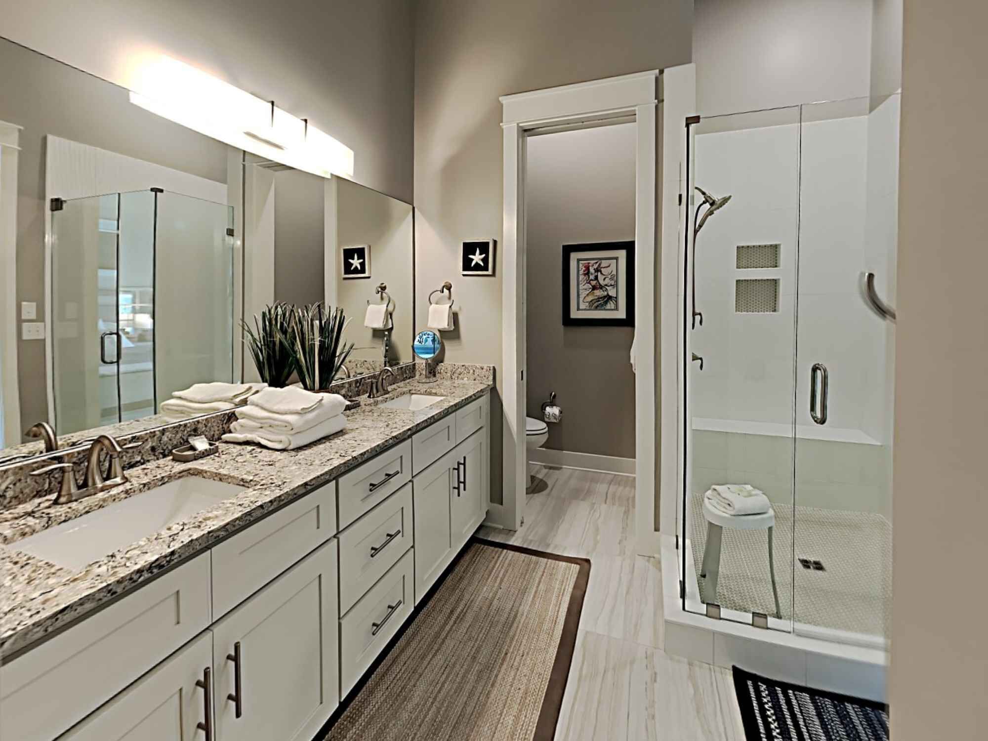 Une salle de bain moderne avec un grand miroir, deux lavabos, une douche et des toilettes.