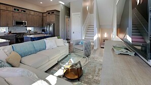 A spacious living area with a modern kitchen, a glass coffee table, and a staircase leading to an upper level. - View From The Top by Southern Vacation Rentals (Santa Rosa Beach)