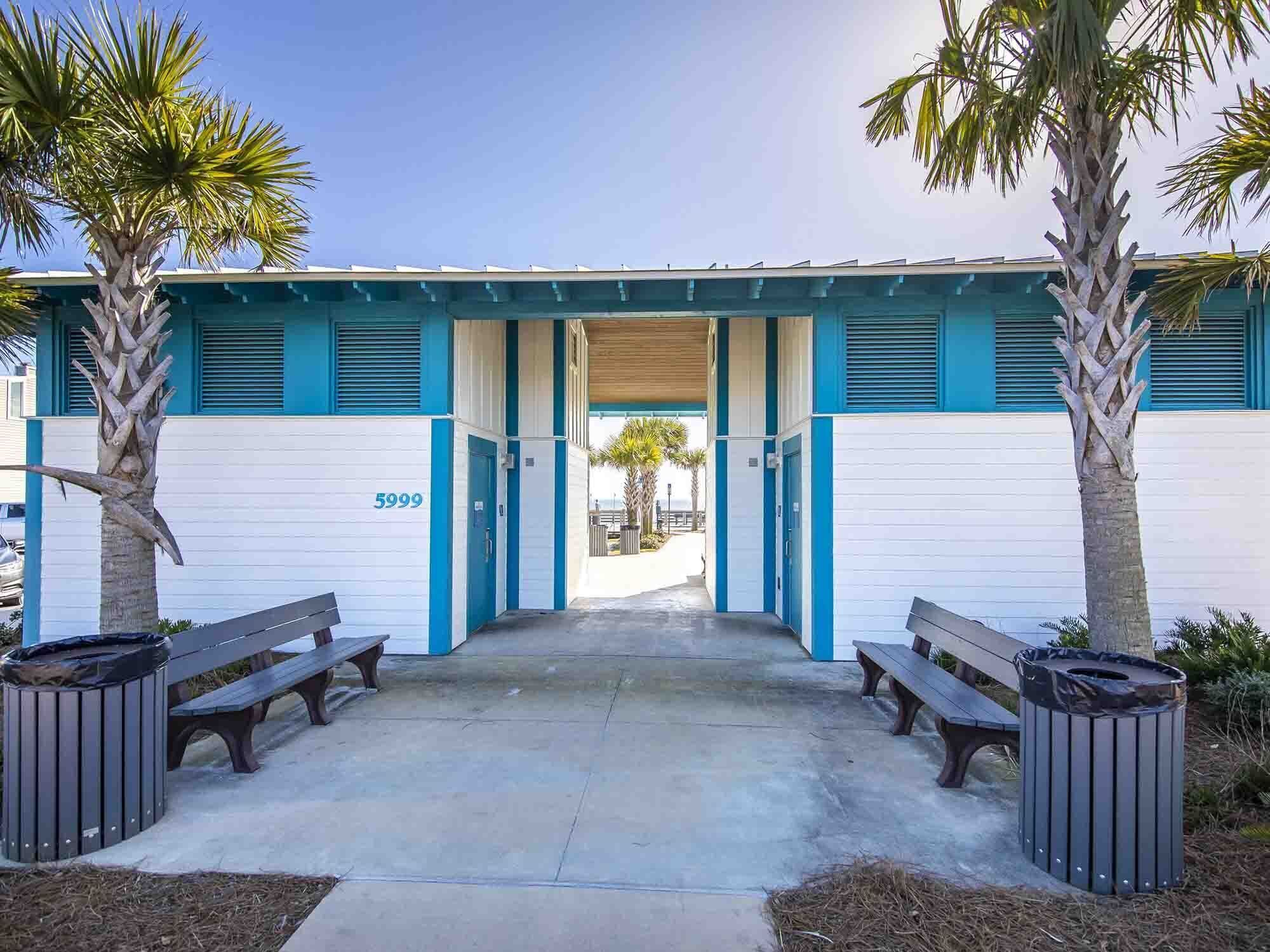 A building with a blue and white facade, numbered 5999, featuring a covered entrance with benches and trash bins.