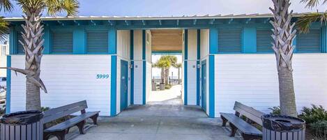 A building with a blue and white facade, numbered 5999, featuring a covered entrance with benches and trash bins.