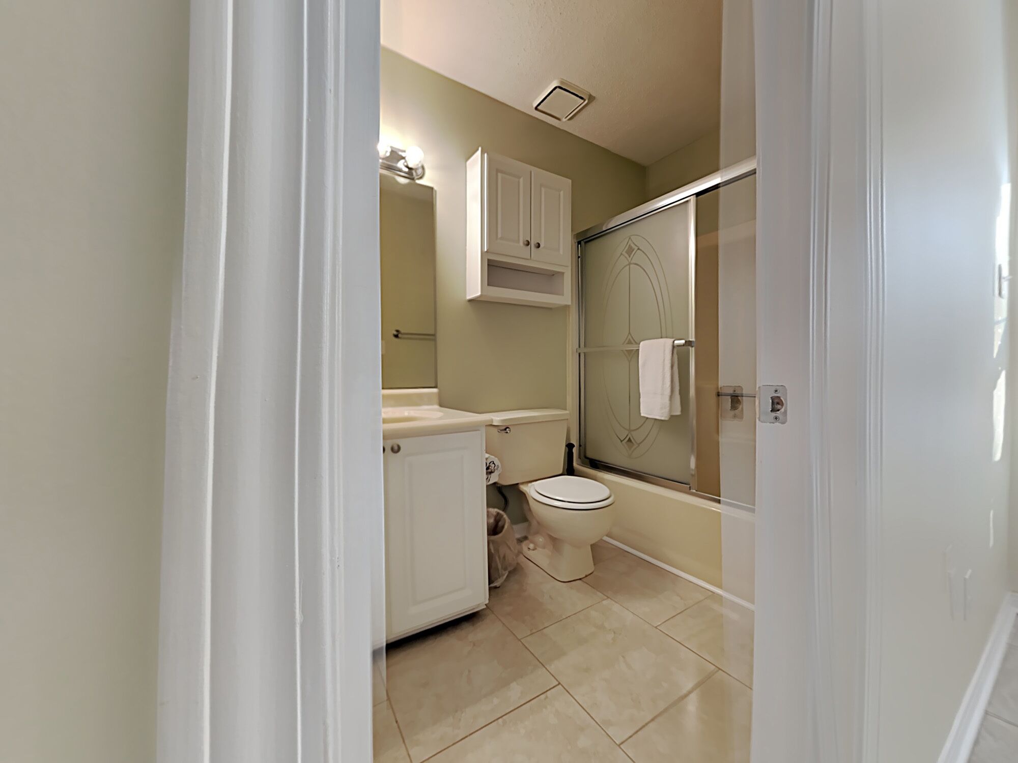 Une salle de bain comprenant des toilettes, un lavabo, un meuble de rangement et un espace douche.