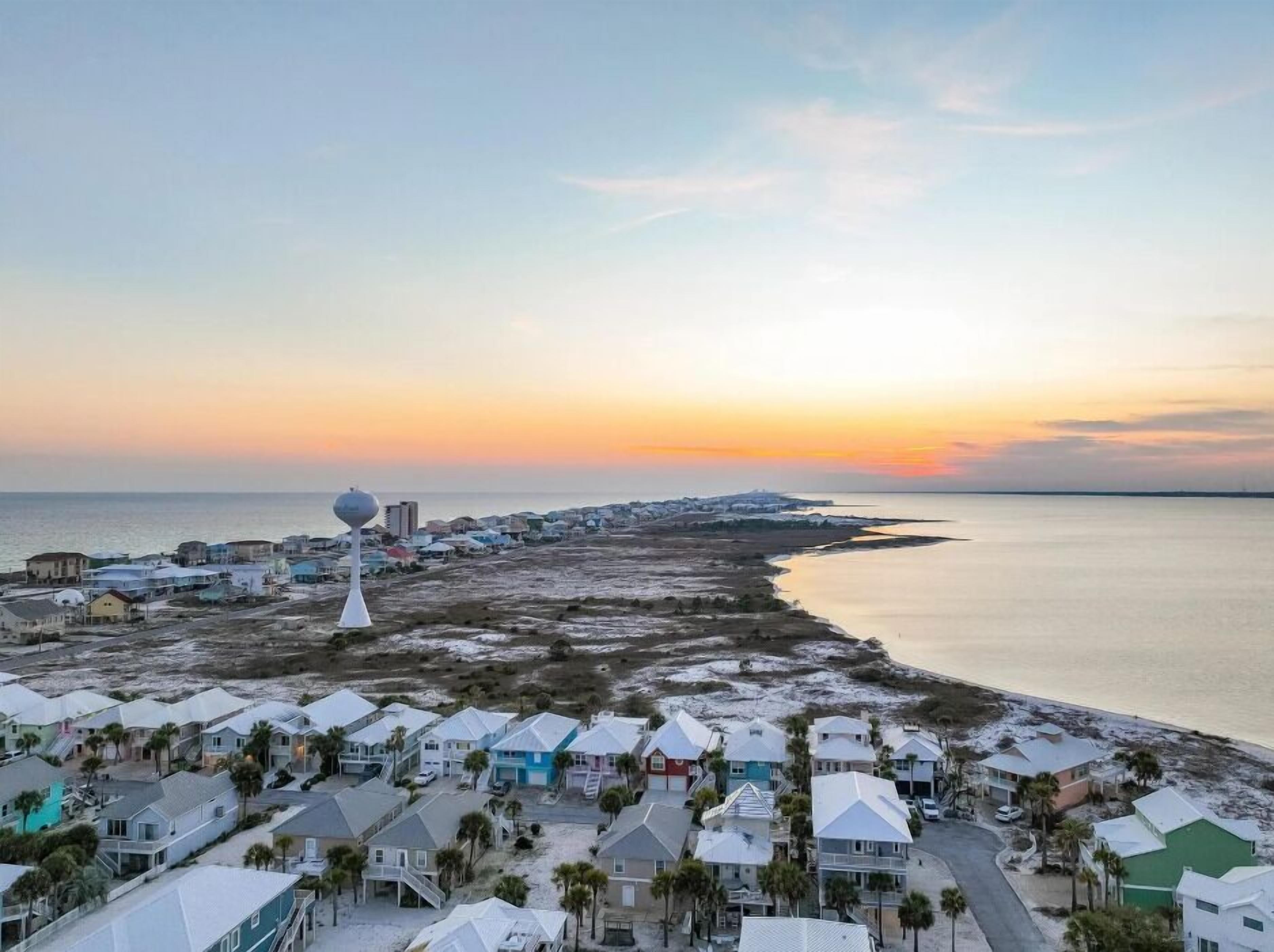 A coastal residential area with houses, a beach, and a lighthouse.