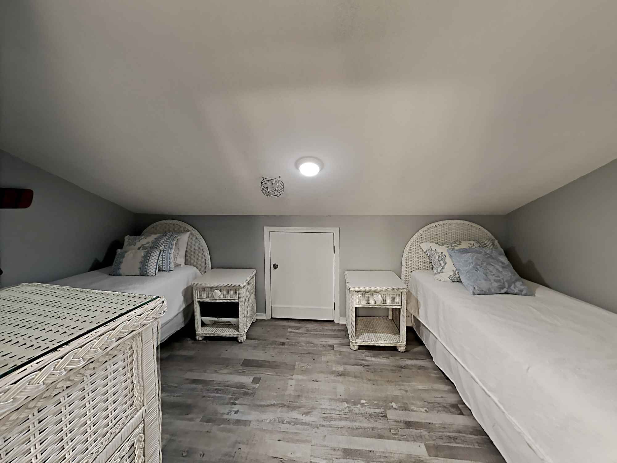 A bedroom with two single beds, a white door, and a small white table between the beds.
