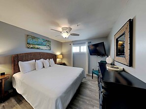 A hotel room with a large bed, a ceiling fan, a TV, a desk, and a window with curtains. - Crystal Sands #311A by Southern Vacation Rentals (Destin)