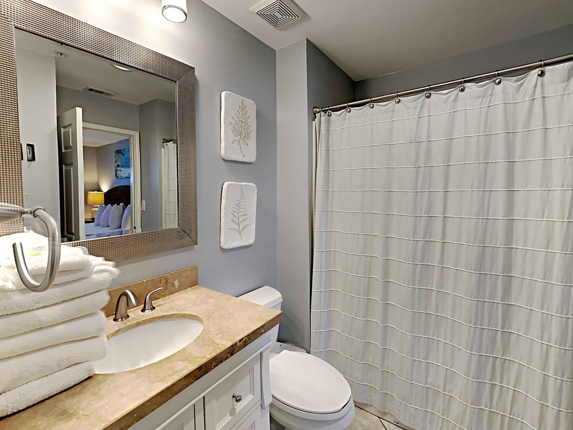 A bathroom with a sink, mirror, towel rack, and a shower curtain.