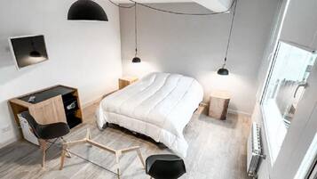 Une chambre à coucher moderne avec un lit, deux tables de chevet, un bureau et une chaise.