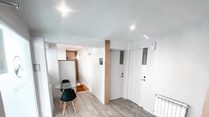 A modern hotel hallway with a glass table and chairs, wooden flooring, and a white radiator. - Hotel Patagonia Signature (San Carlos de Bariloche)
