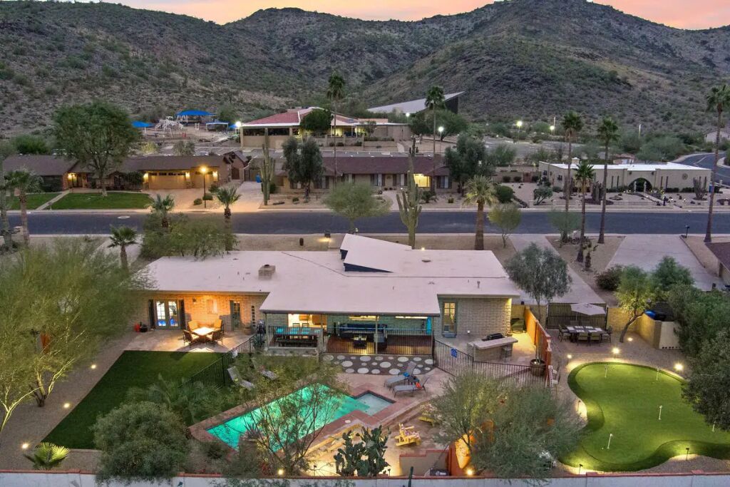 A residential area with a swimming pool, multiple houses, and a hilly backdrop.