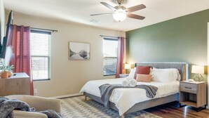 A bedroom with a bed, bedside tables, a ceiling fan, and a window with curtains.