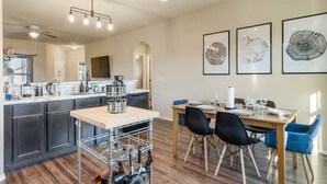 A modern kitchen with dark cabinets, a wooden countertop, and a dining area with a table and chairs.