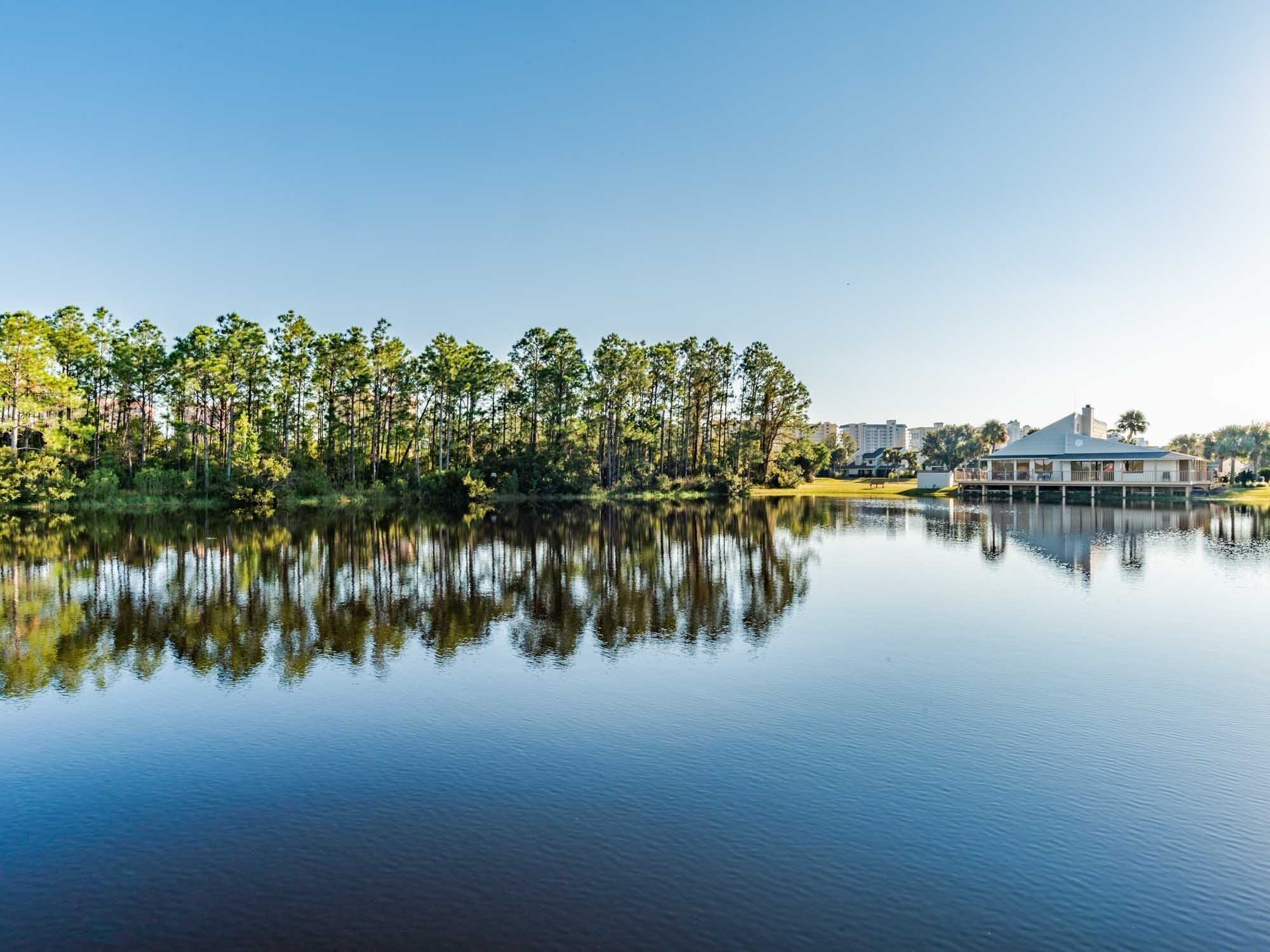 A serene lakeside view with a reflection of trees and a building.