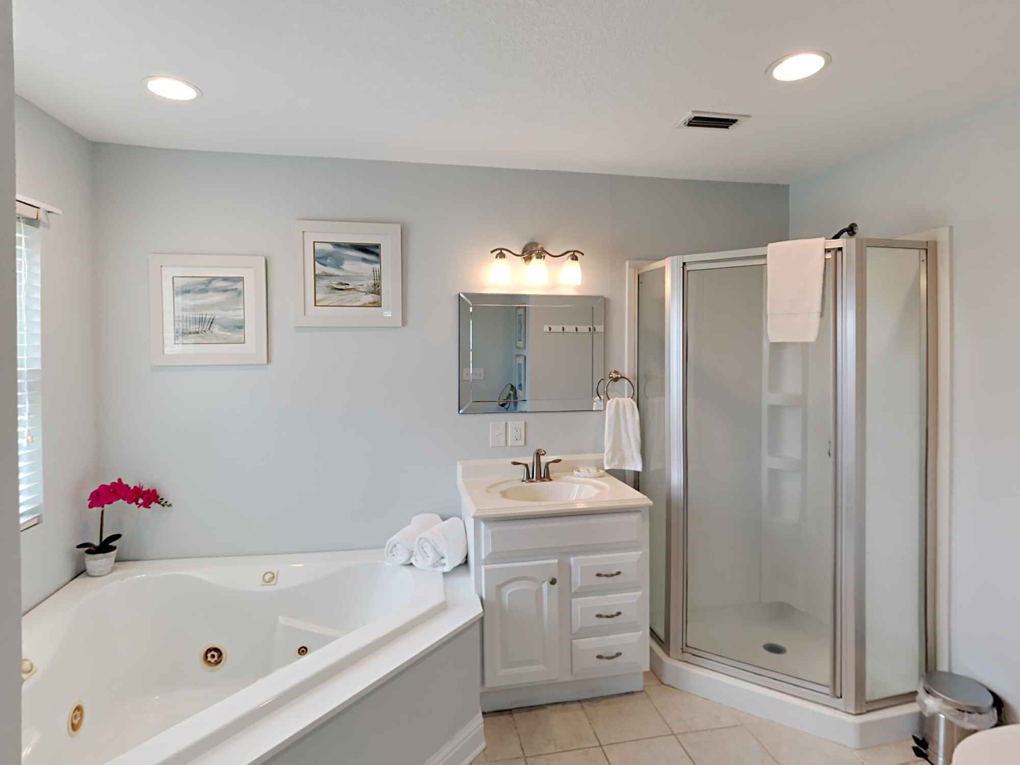 A bathroom with a bathtub, vanity, and walk-in shower.